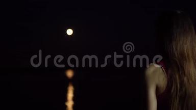 一个黑发的年轻女子欣赏河中倒影的红月。